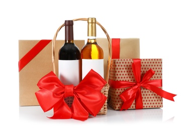 Photo of Festive basket with bottles of wine and gift boxes on white background