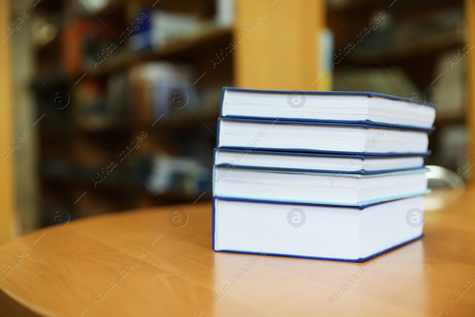Photo of Stack of books on table in library. Space for text