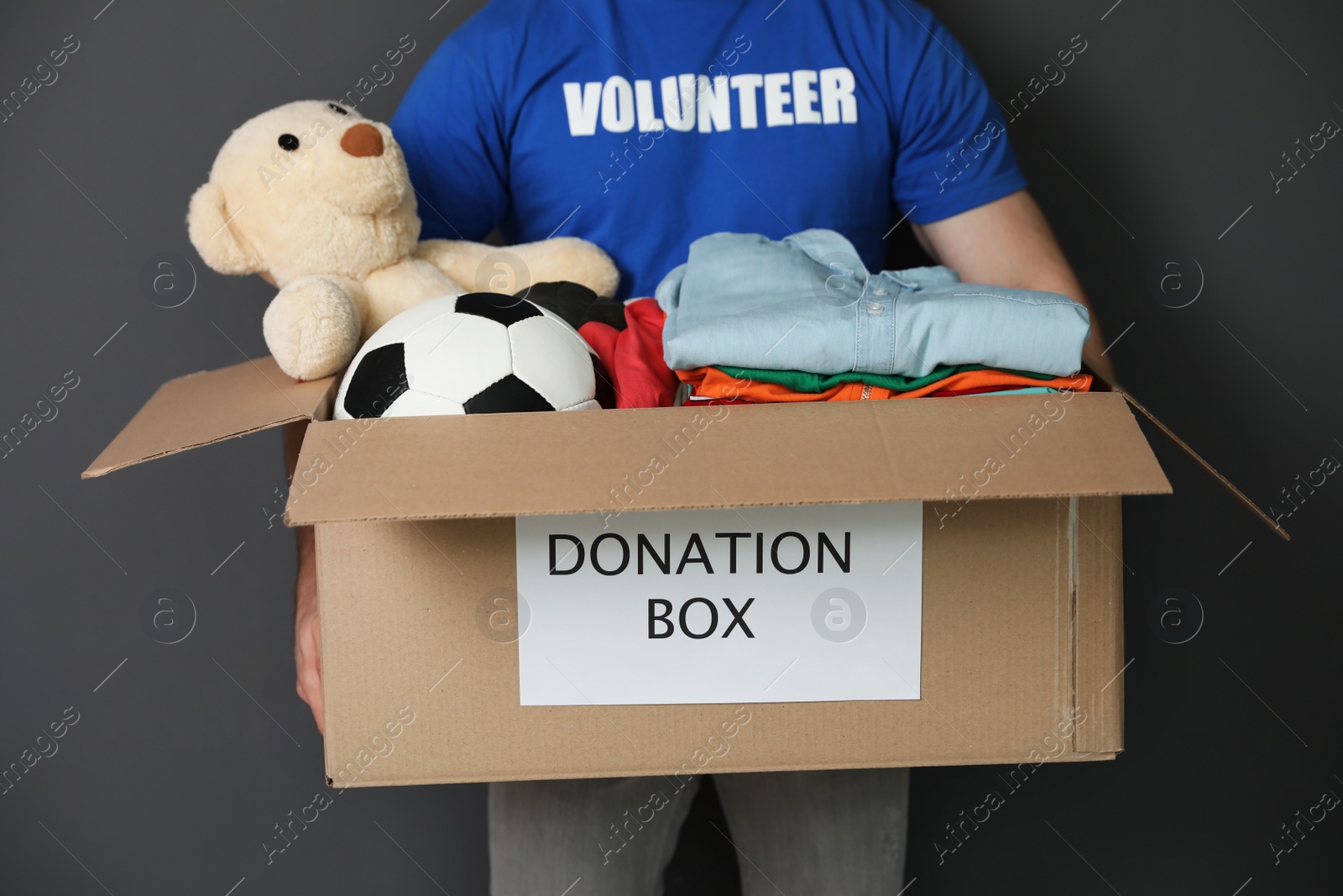 Photo of Male volunteer holding box with donations on grey background