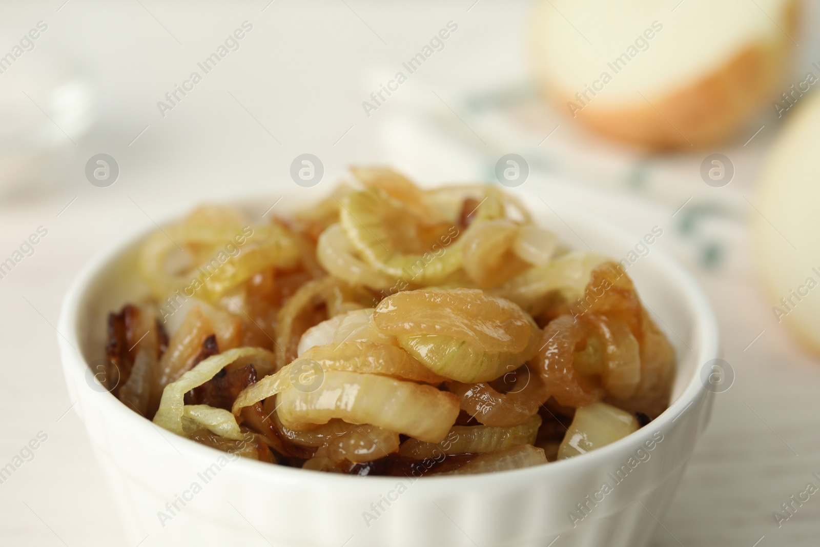 Photo of Tasty fried onion in bowl on light background, closeup