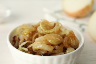 Tasty fried onion in bowl on light background, closeup