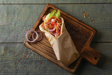 Photo of Delicious pita wrap with vegetables and meat on dark wooden table, top view