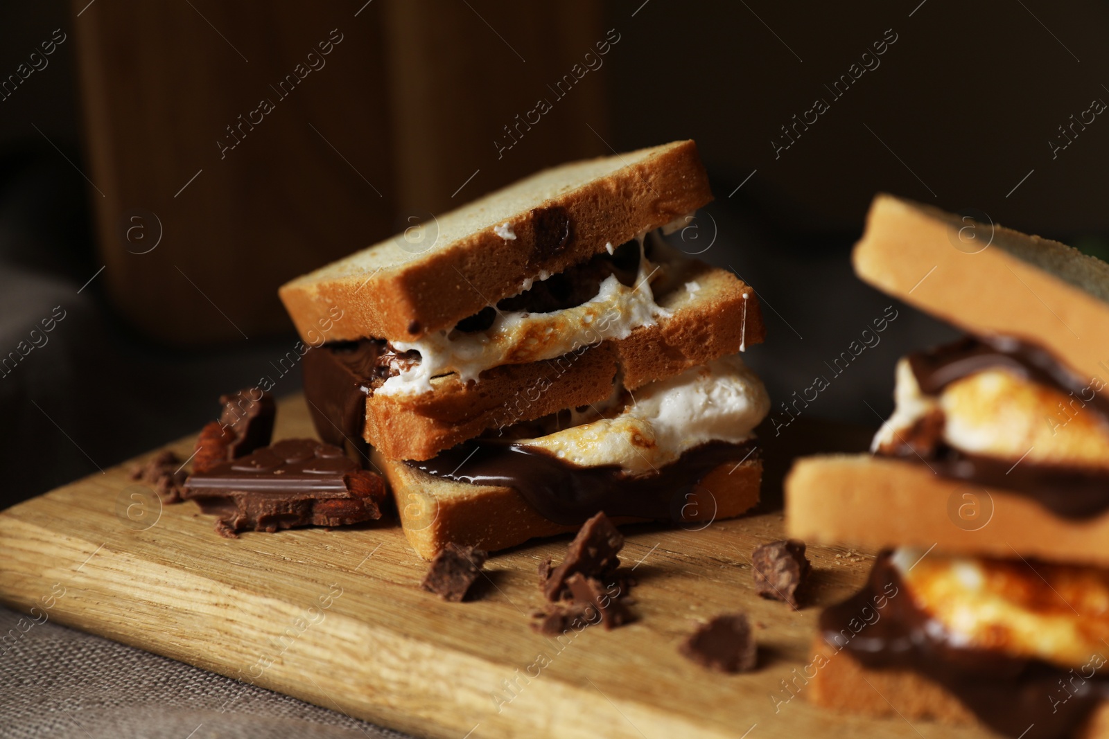 Photo of Delicious marshmallow sandwiches with bread and chocolate on wooden board, closeup