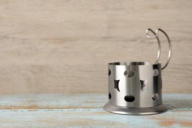 Photo of Traditional tea glass holder on light blue wooden table, space for text