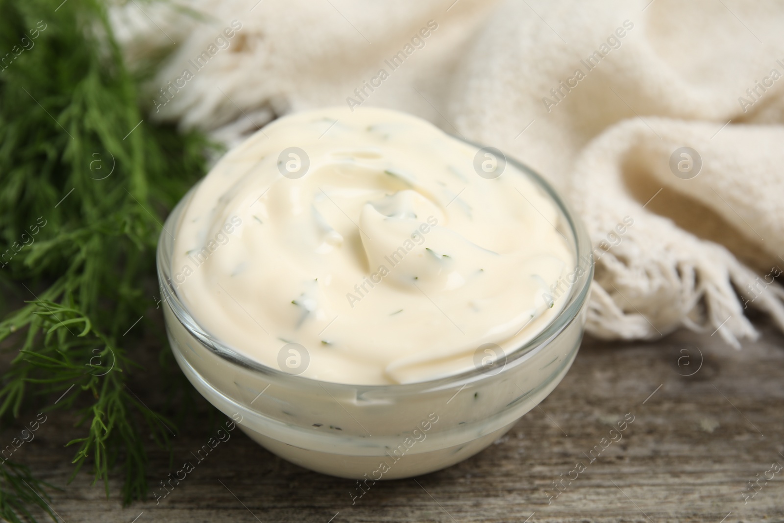 Photo of Tasty creamy sauce and fresh dill on wooden table, closeup