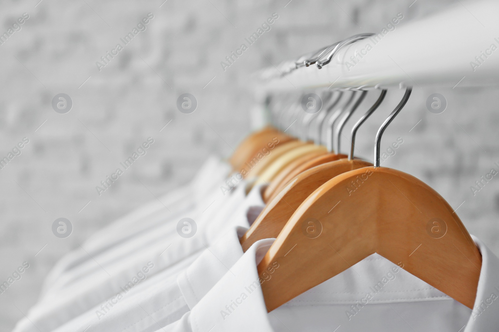 Photo of Rack with clean clothes on hangers after dry-cleaning, closeup