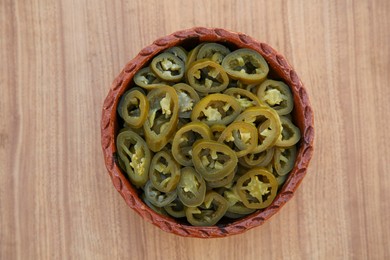 Photo of Pickled green jalapeno peppers on wooden table, top view