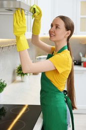 Photo of Woman cleaning kitchen hood with rag indoors