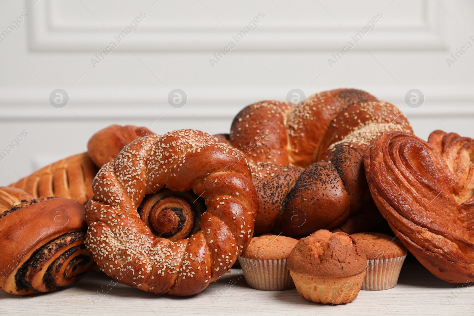 Photo of Different tasty freshly baked pastries on white wooden table, closeup