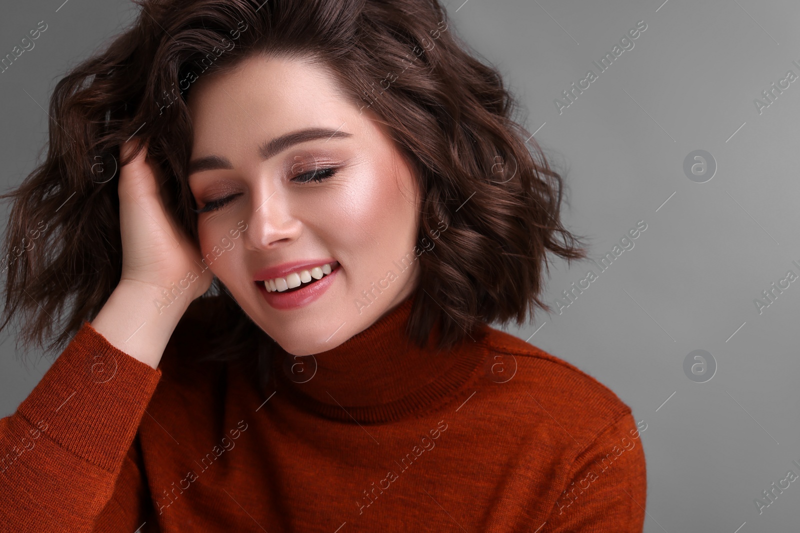 Photo of Beautiful young woman with wavy hairstyle on grey background