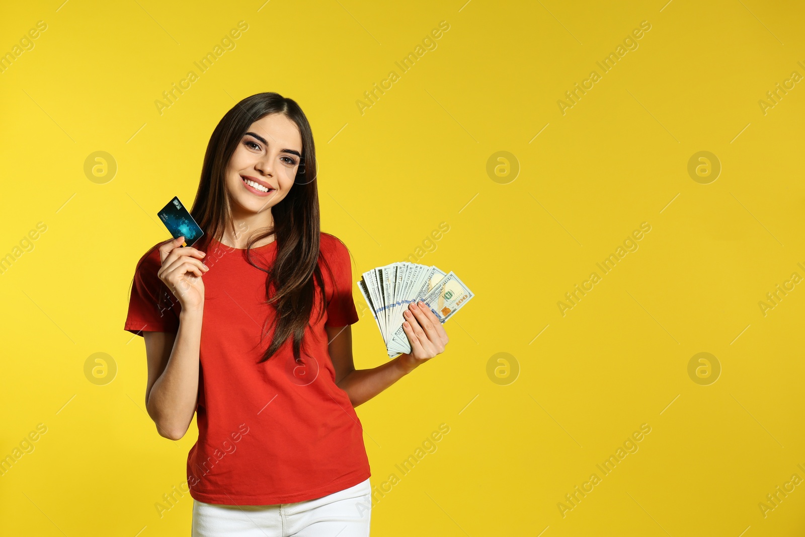 Photo of Young woman with money and credit card on color background. Space for text