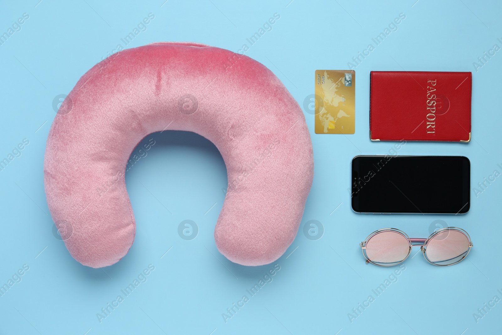 Photo of Flat lay composition with pink travel pillow and smartphone on light blue background