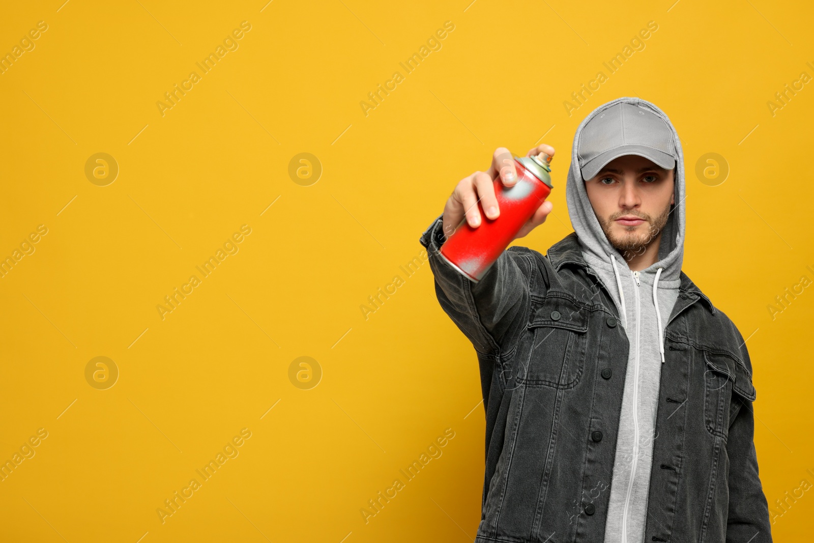 Photo of Handsome man holding can of spray paint on yellow background. Space for text