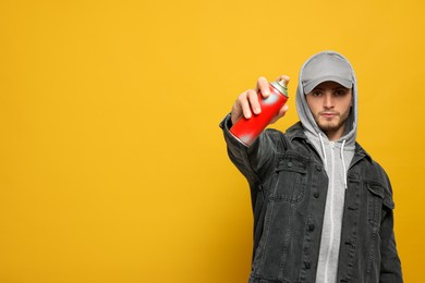 Photo of Handsome man holding can of spray paint on yellow background. Space for text