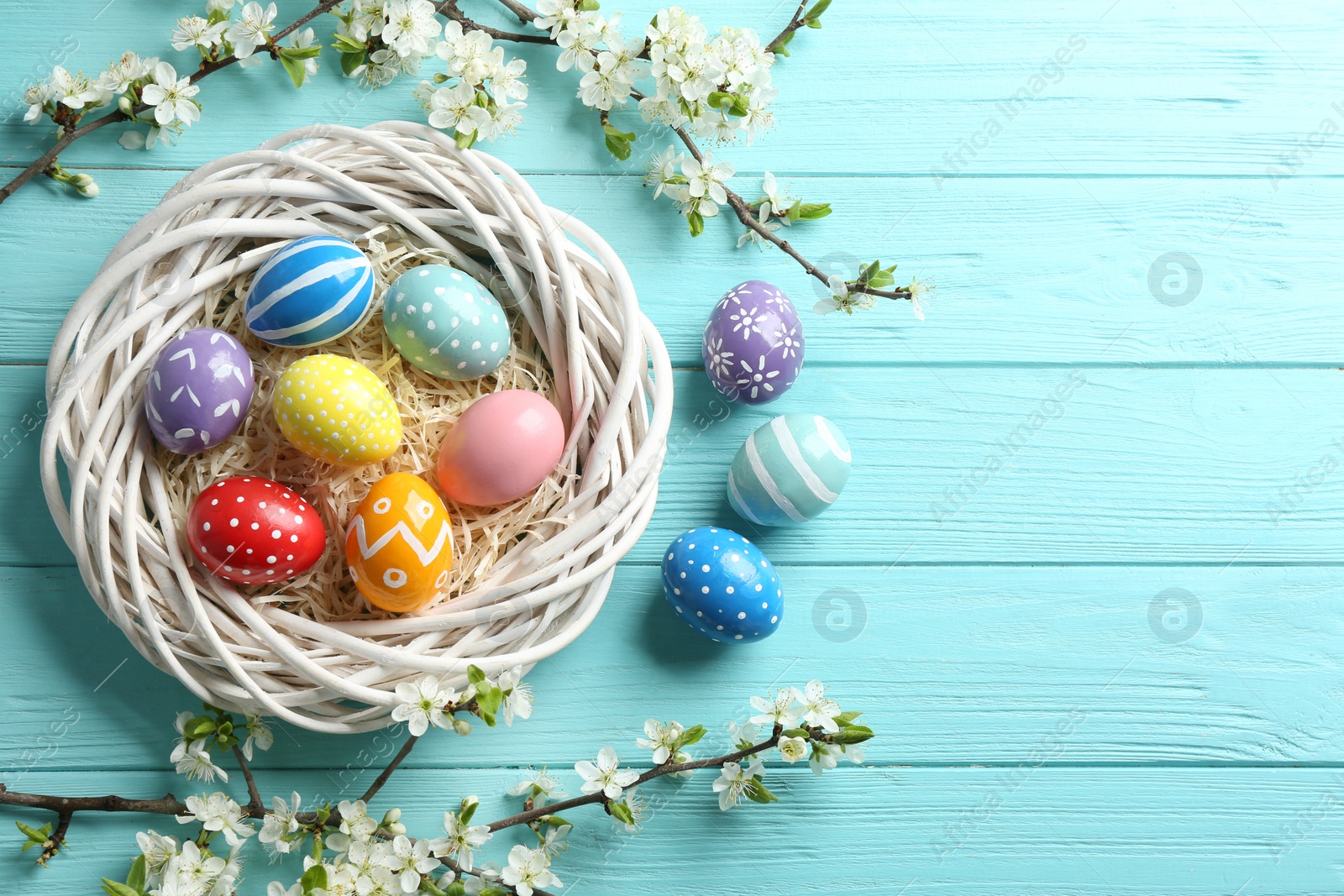 Photo of Flat lay composition with painted Easter eggs and blossoming branches on wooden background. Space for text