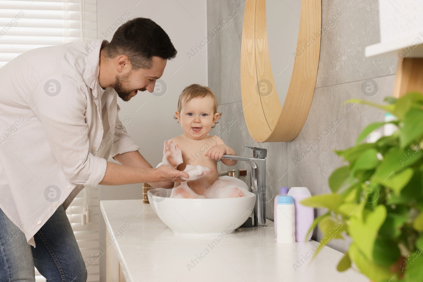 Photo of Father washing his little baby in sink at home