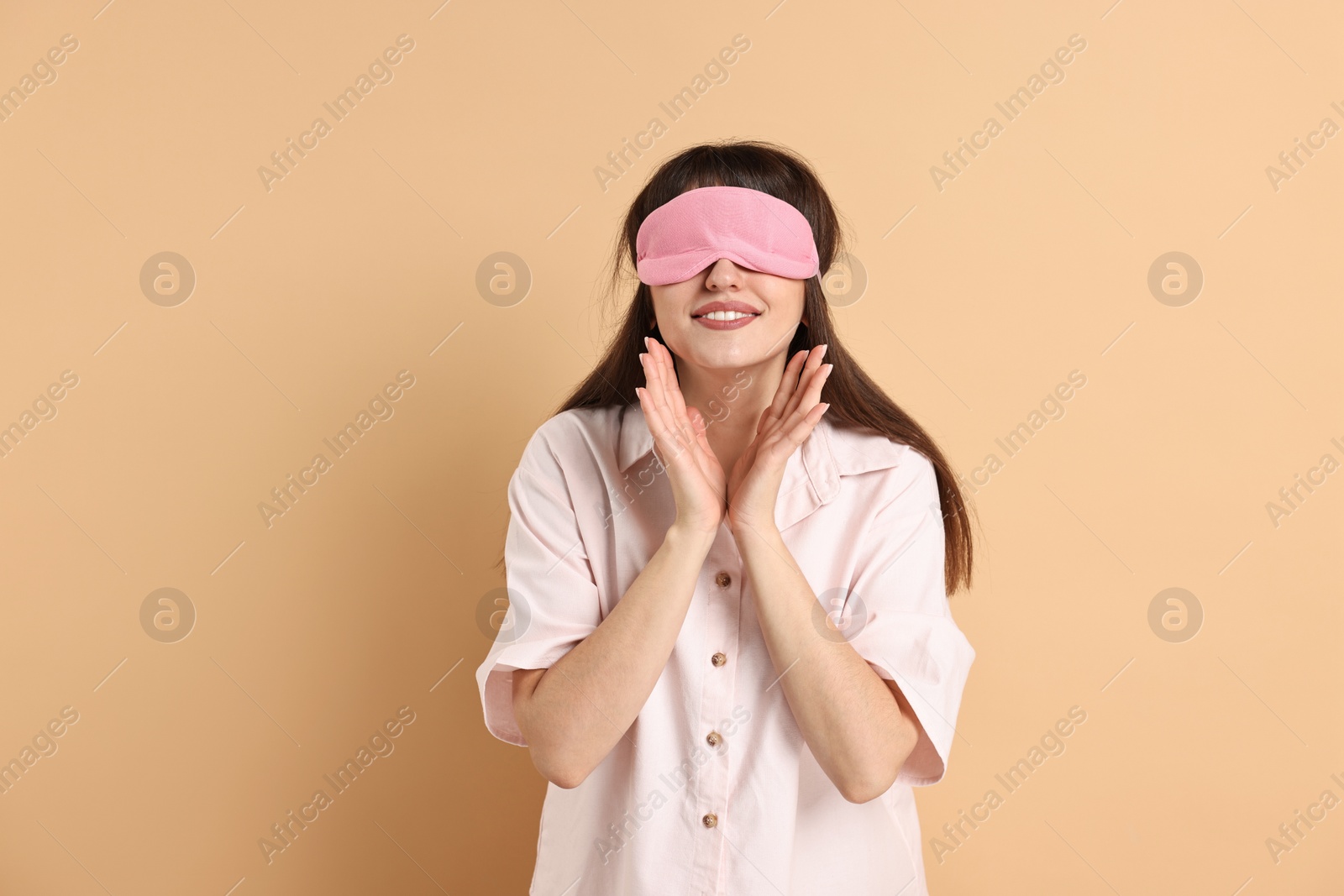 Photo of Woman in pyjama and sleep mask on beige background