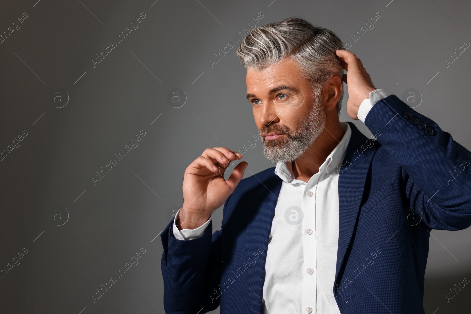 Photo of Portrait of confident man with beautiful hairstyle on dark grey background. Space for text