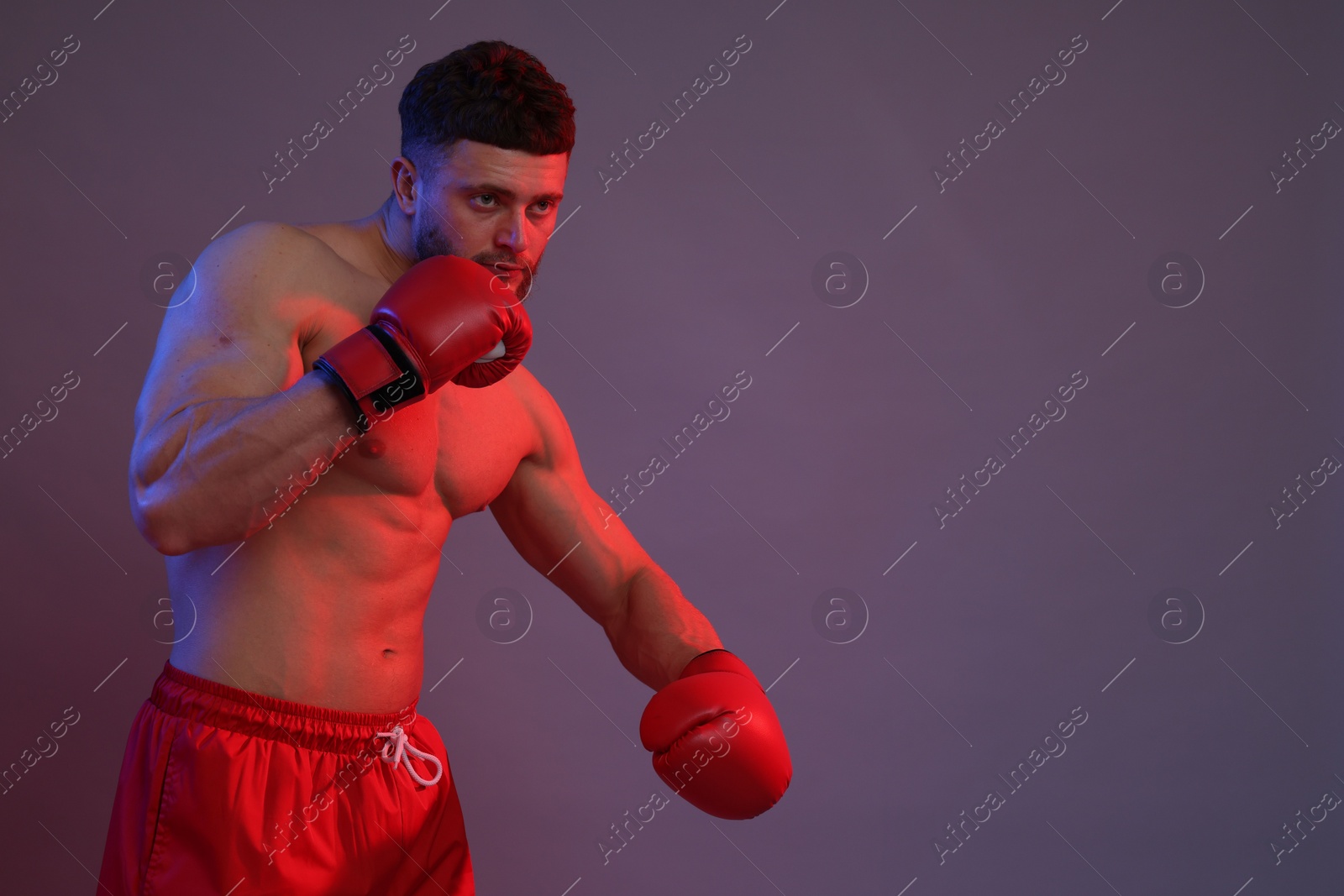 Photo of Man in boxing gloves fighting on color background. Space for text