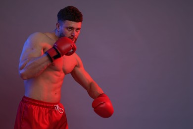 Man in boxing gloves fighting on color background. Space for text