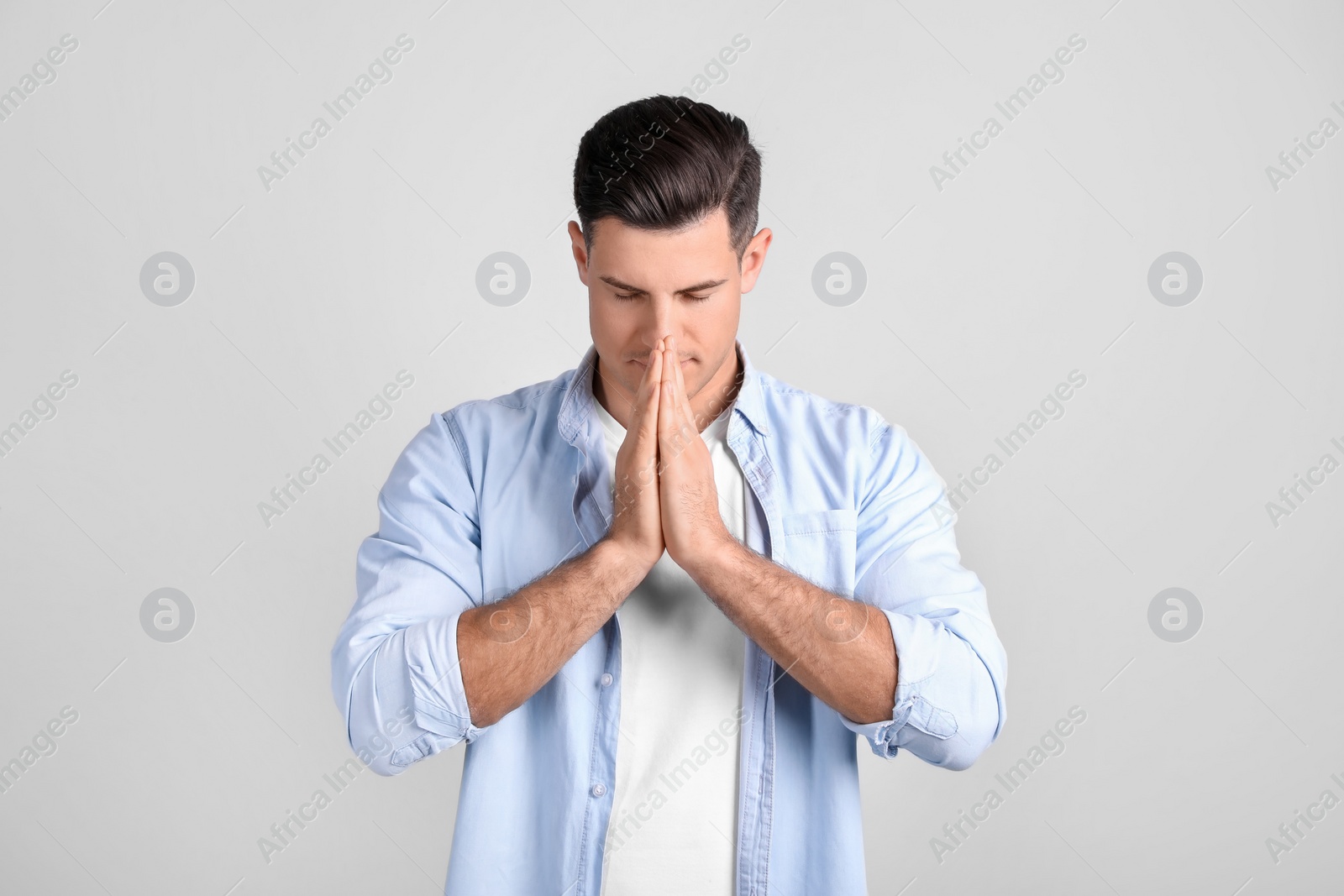 Photo of Man meditating on light background. Stress relief exercise