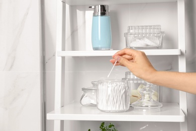 Young woman taking cotton swab from jar indoors, closeup