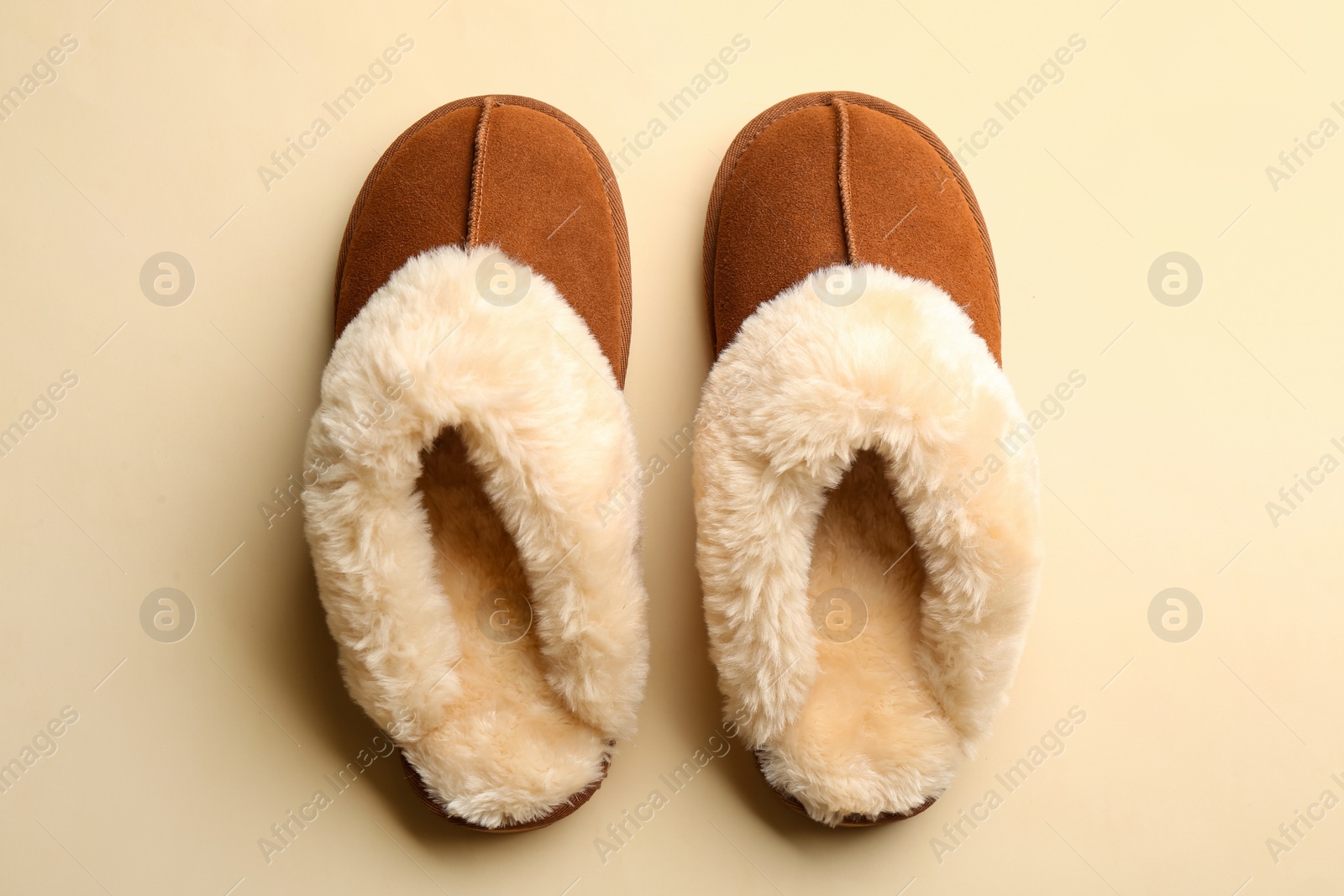 Photo of Pair of stylish soft slippers on beige background, flat lay