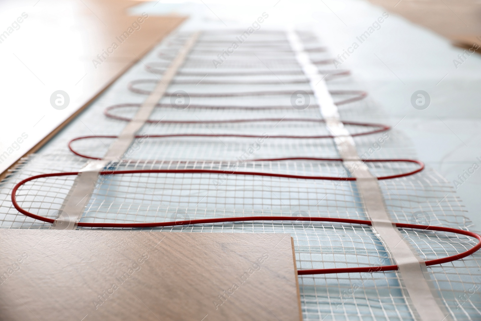 Photo of Installation of modern underfloor trace heating system indoors, closeup