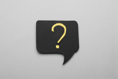 Paper speech bubble with question mark on light grey background, top view