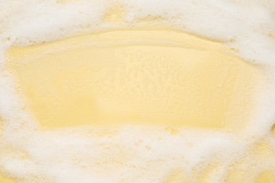 White washing foam on yellow background, top view