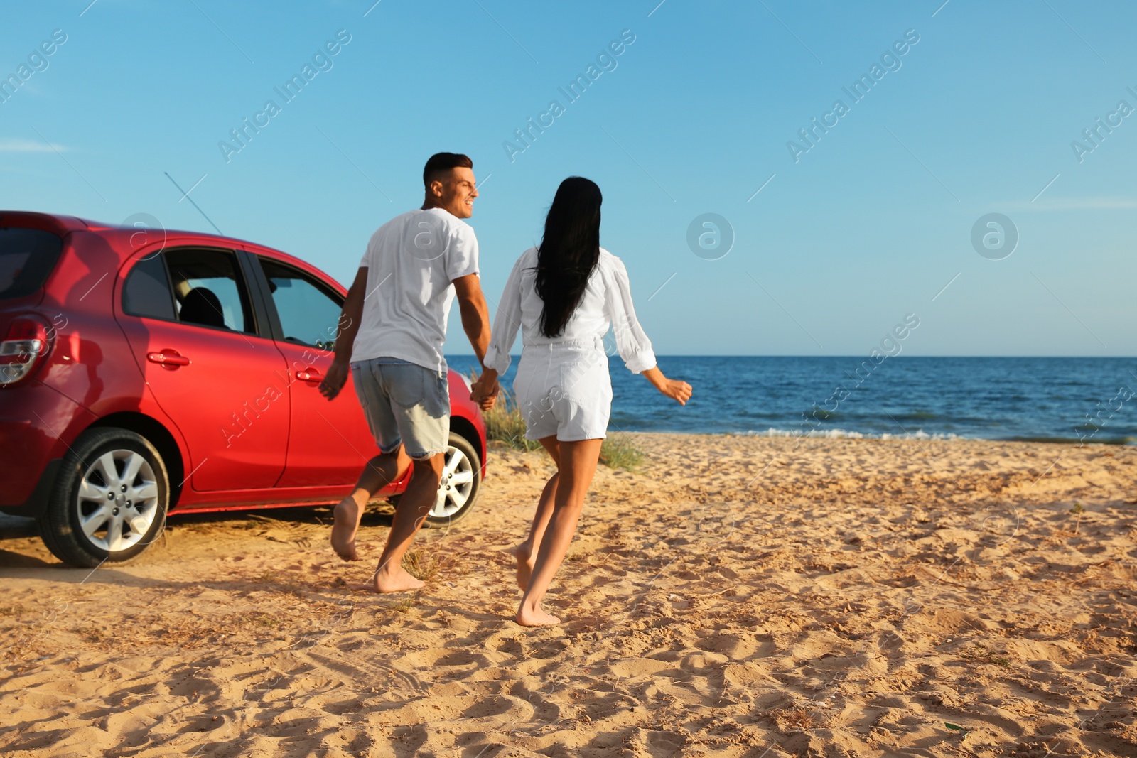 Photo of Lovely couple running on sandy beach. Summer trip