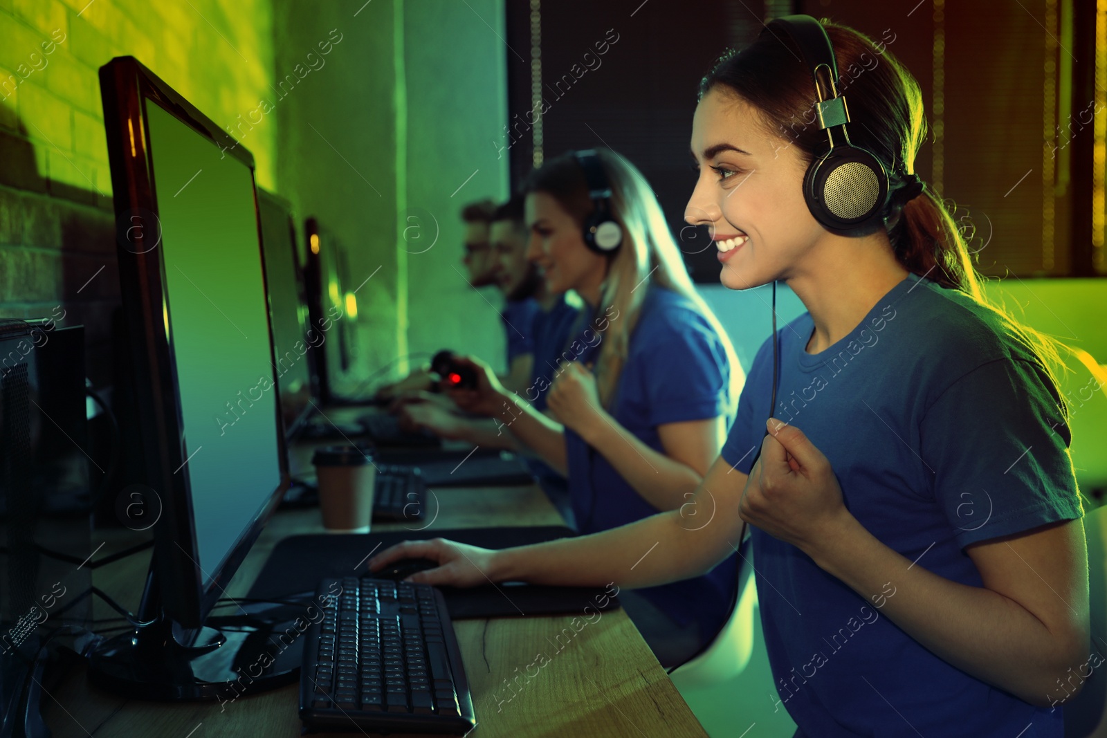 Photo of Group of people playing video games in internet cafe, color tone