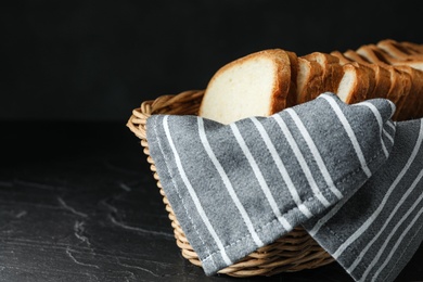 Photo of Slices of bread in basket on table against black background