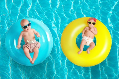 Image of Cute little babies with inflatable rings in swimming pool, top view