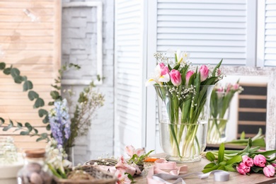 Photo of Decorator's workplace with beautiful flowers on table