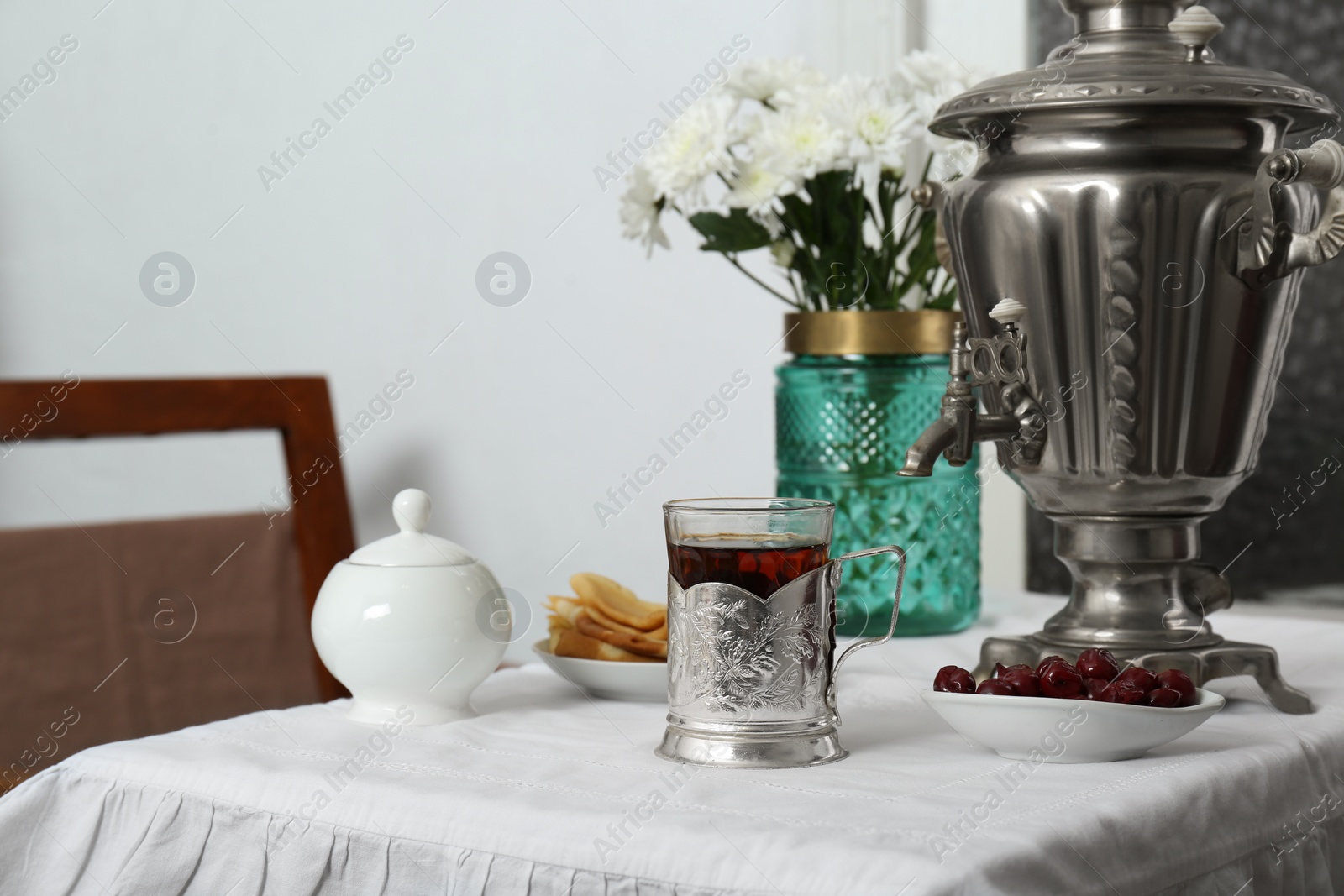 Photo of Traditional Russian samovar, aromatic tea and treats on table indoors
