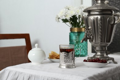 Traditional Russian samovar, aromatic tea and treats on table indoors