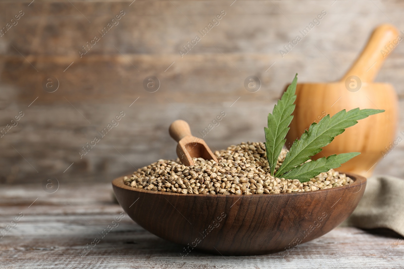 Photo of Bowl of hemp seeds on table against wooden wall