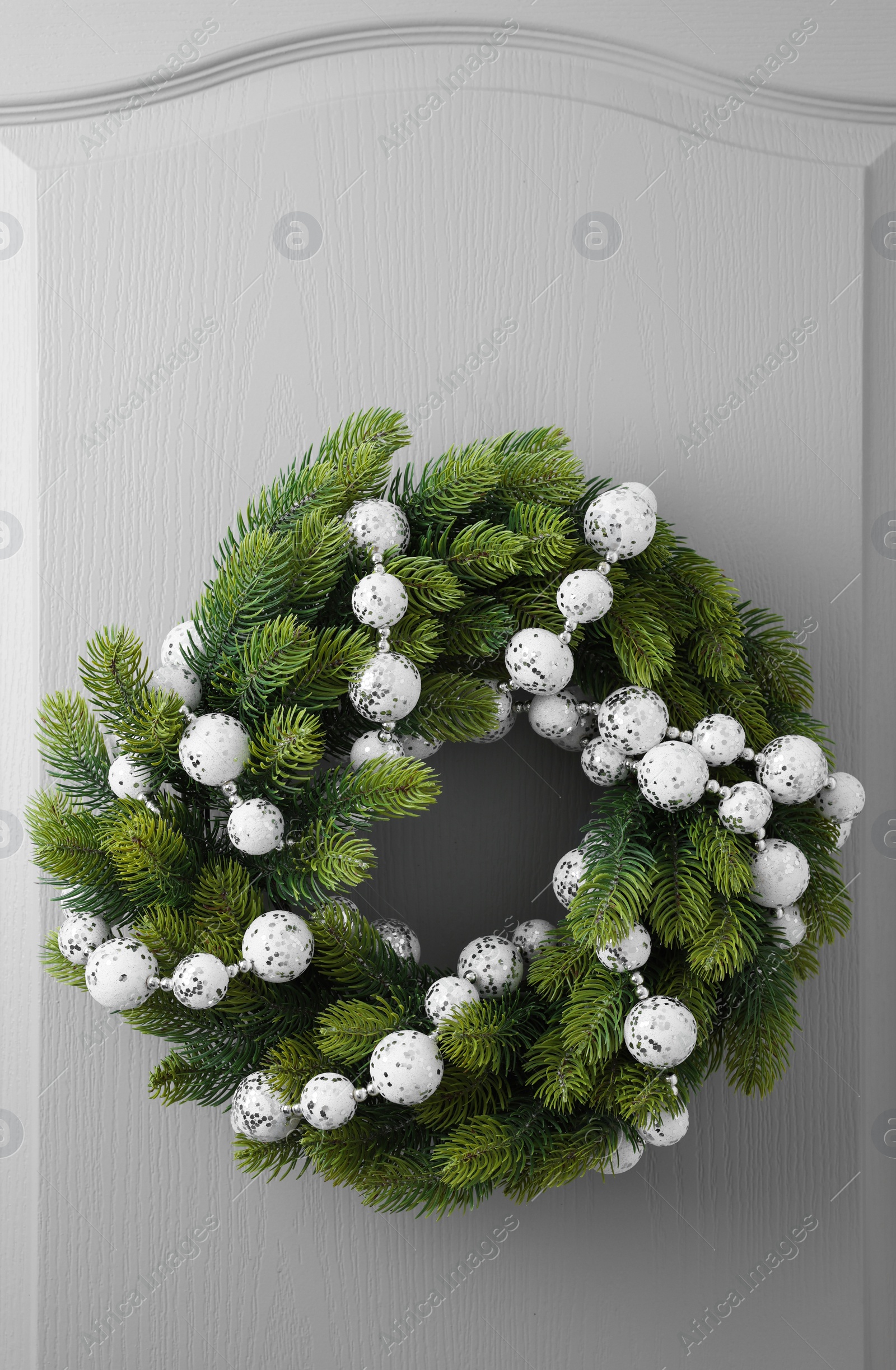 Photo of Beautiful Christmas wreath with festive decor hanging on white door