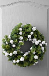 Beautiful Christmas wreath with festive decor hanging on white door