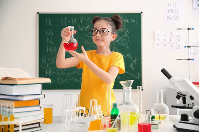 Photo of Schoolchild making experiment at table in chemistry class