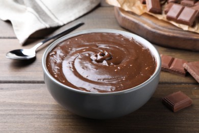 Delicious chocolate cream in bowl on wooden table