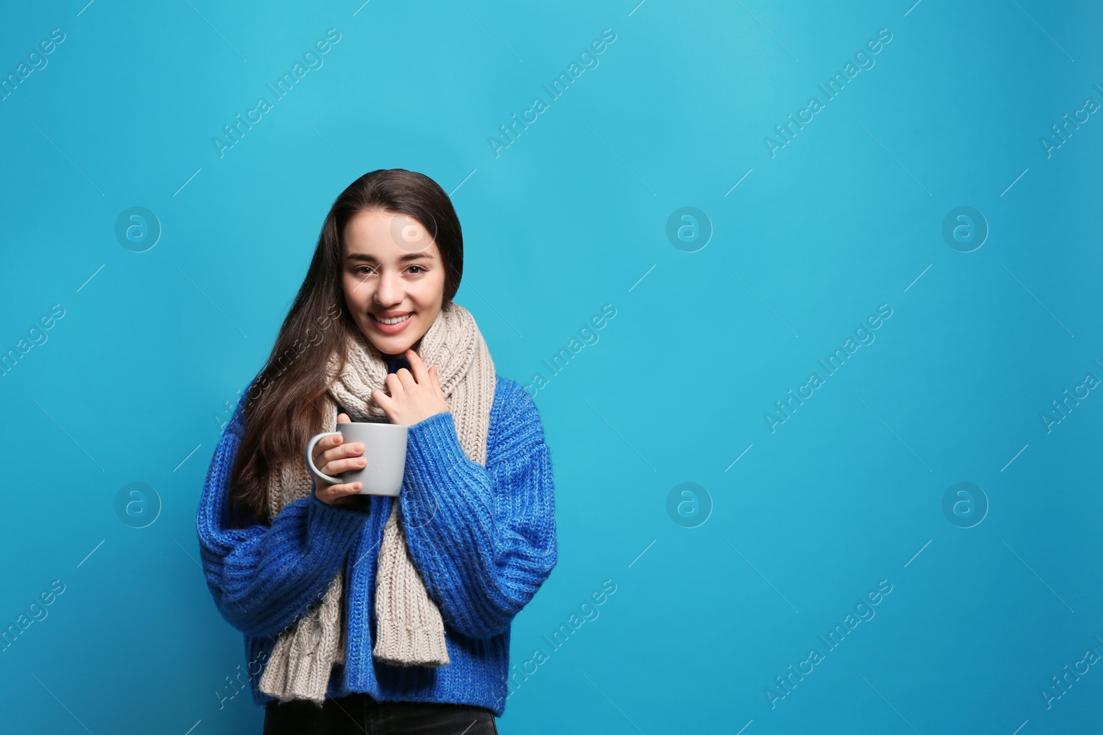 Photo of Young woman in sweater with cup of hot coffee on color background, space for text. Winter season