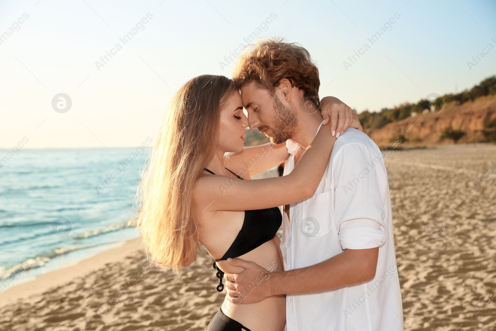 Photo of Romantic young couple in beachwear spending time together on seashore