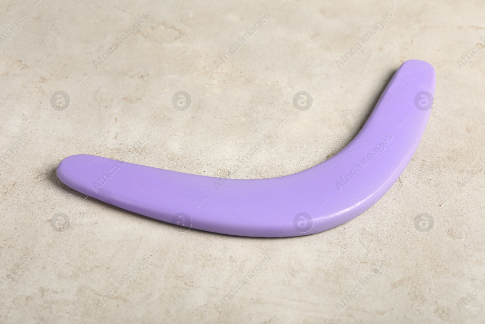 Photo of Purple boomerang on light grey background. Outdoors activity