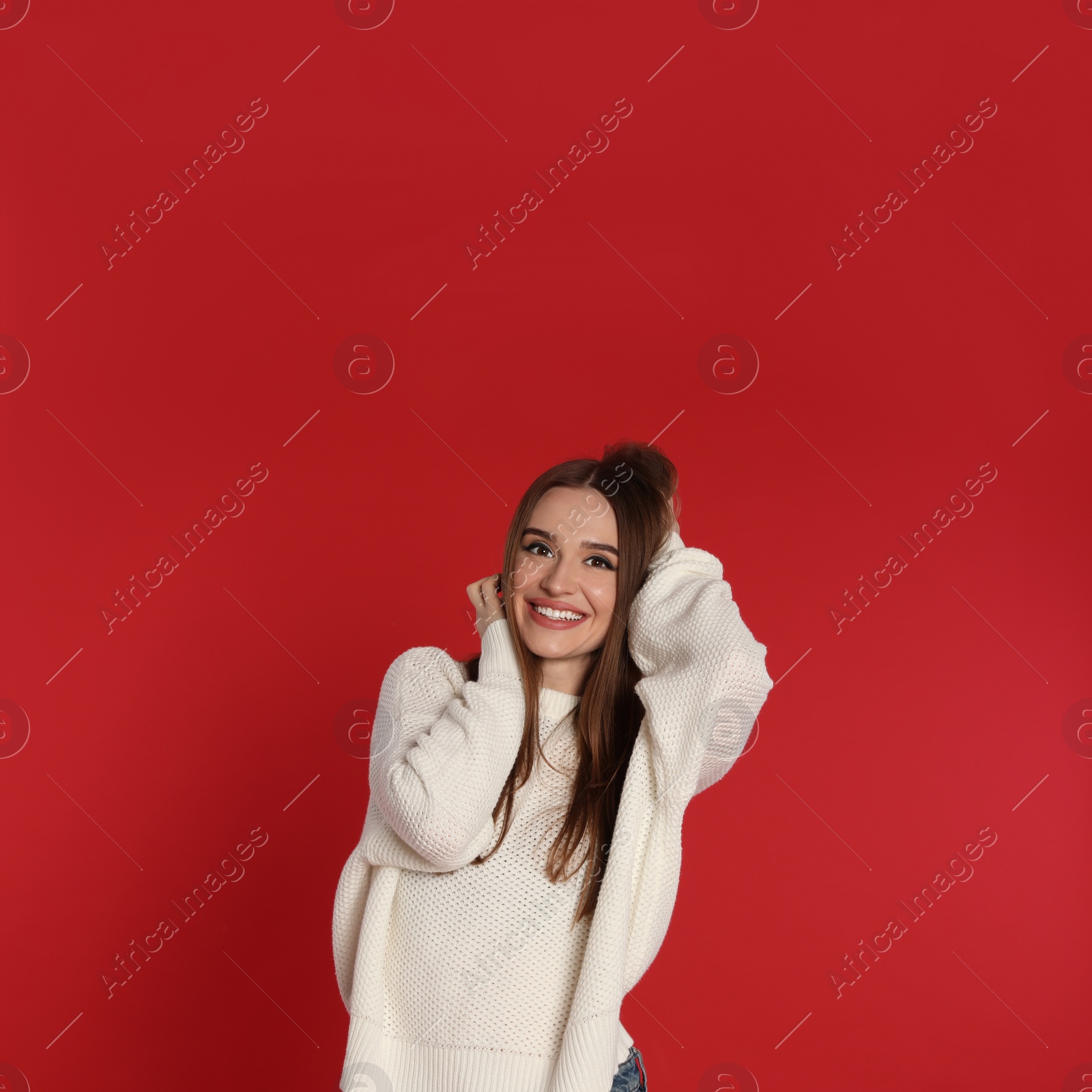 Photo of Beautiful young woman in white sweater on red background. Winter season