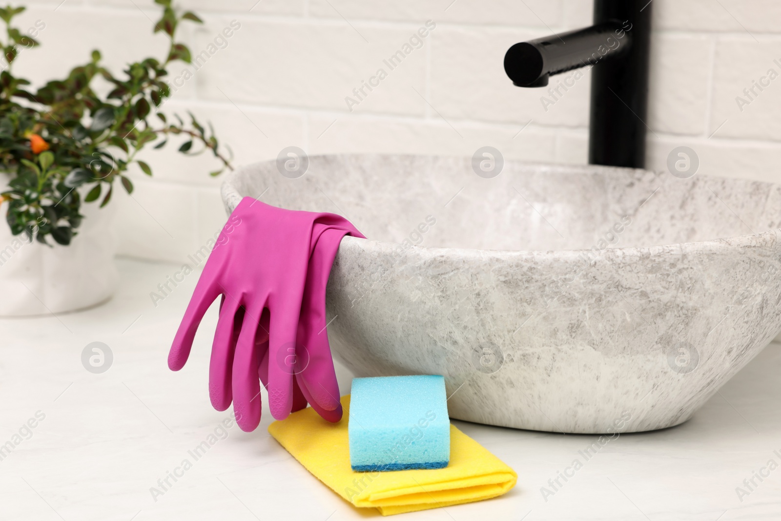 Photo of Sponge, rag and rubber gloves near sink in bathroom