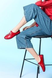 Photo of Fashionable woman in stylish shoes on stool against color background, closeup