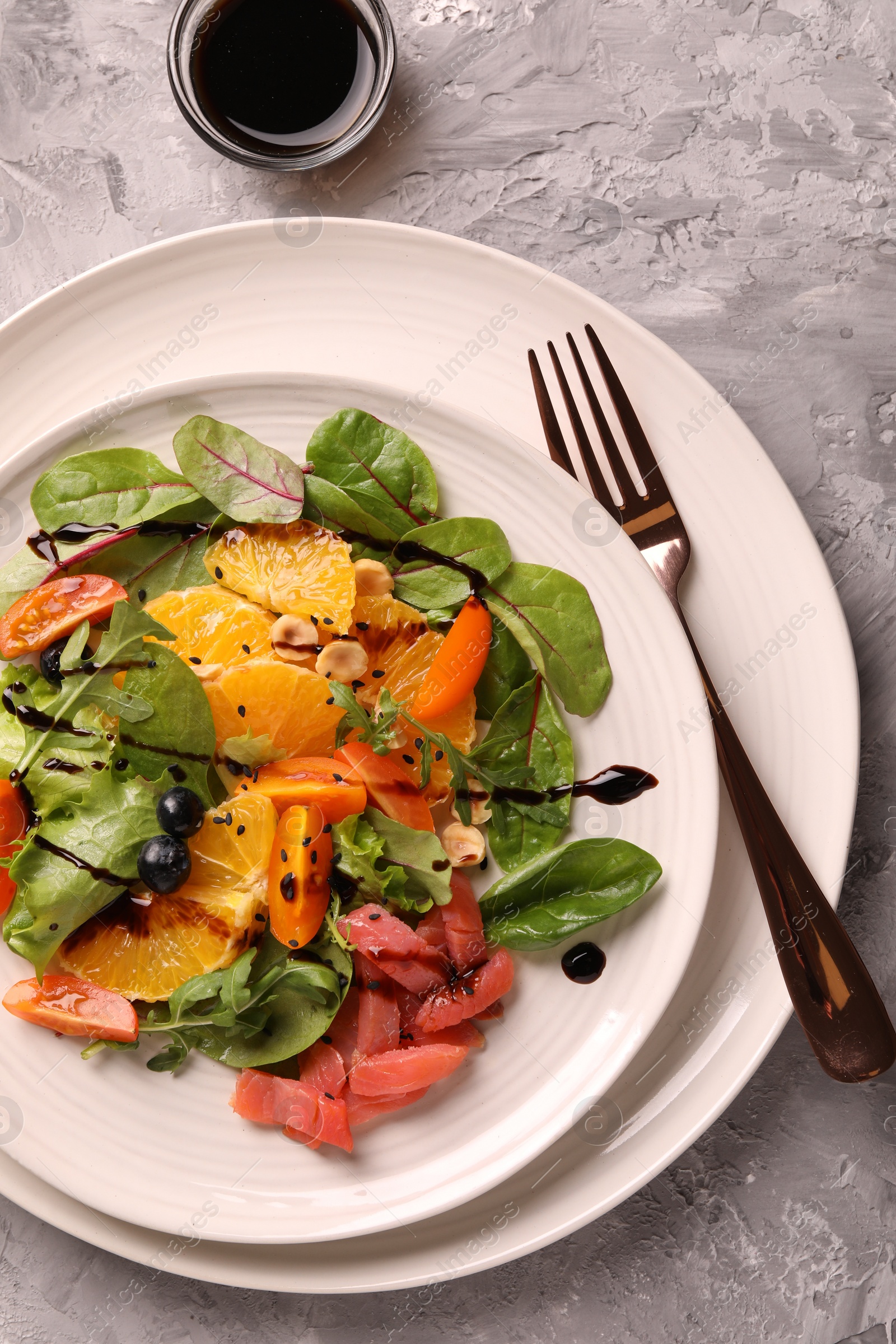 Photo of Delicious salad with salmon served on gray textured table, flat lay