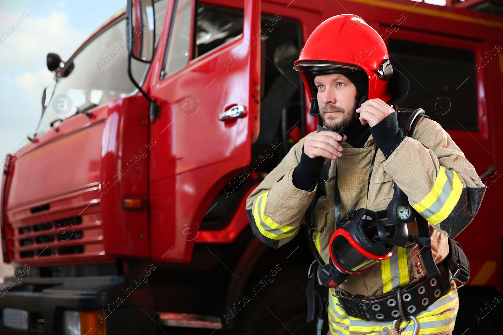 Photo of Firefighter in uniform near red fire truck at station